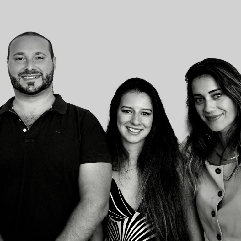 Três profissionais da equipe franco-brasileira Good Times Production Brasil sorrindo em foto corporativa preto e branco