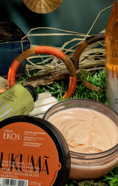 Produtos Natura Ekos linha Tukumã com bálsamo corporal, óleo de banho e creme para mãos em cenário natural